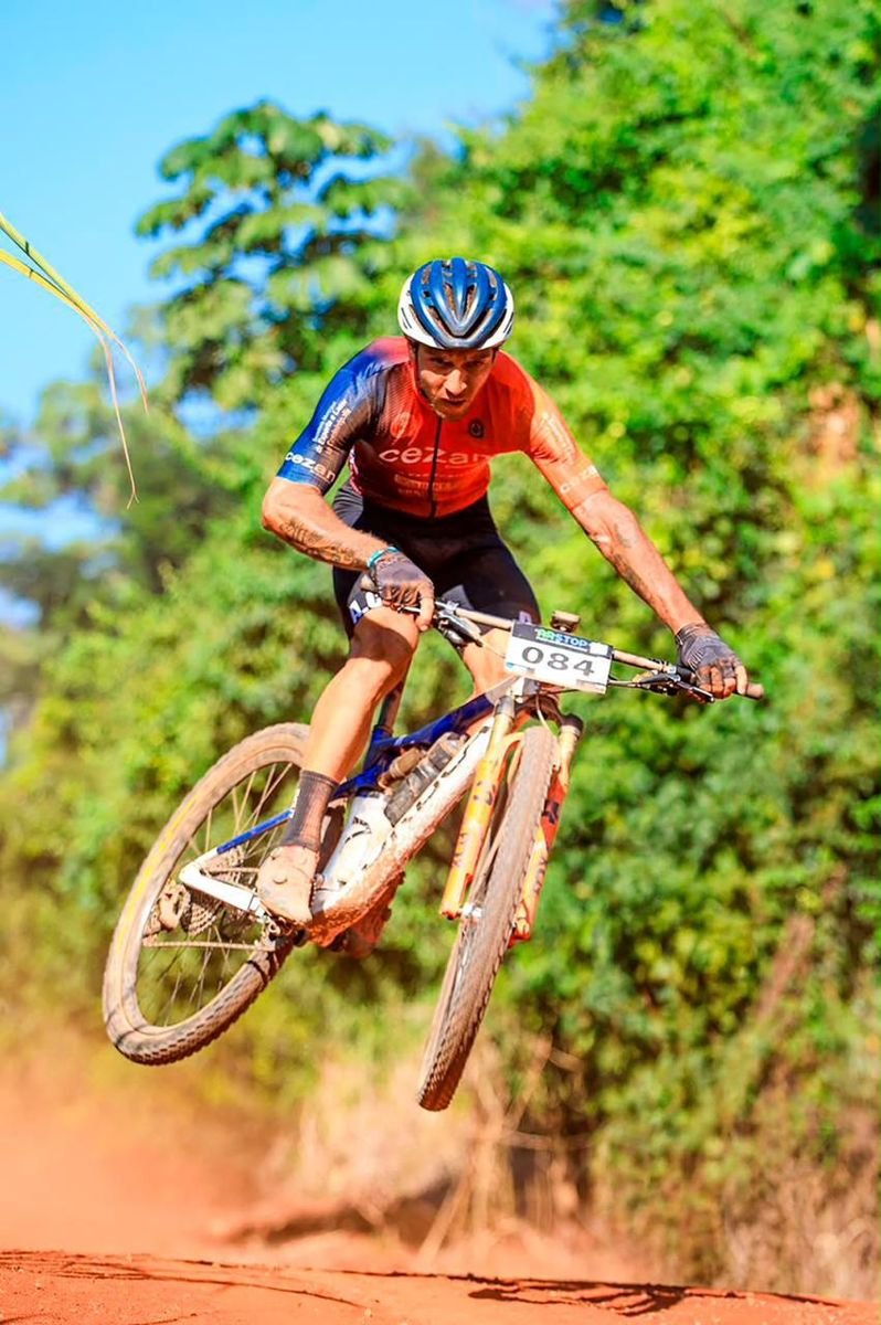 Matheus, atleta da ACC, saltando com a bike em trilha de terra
